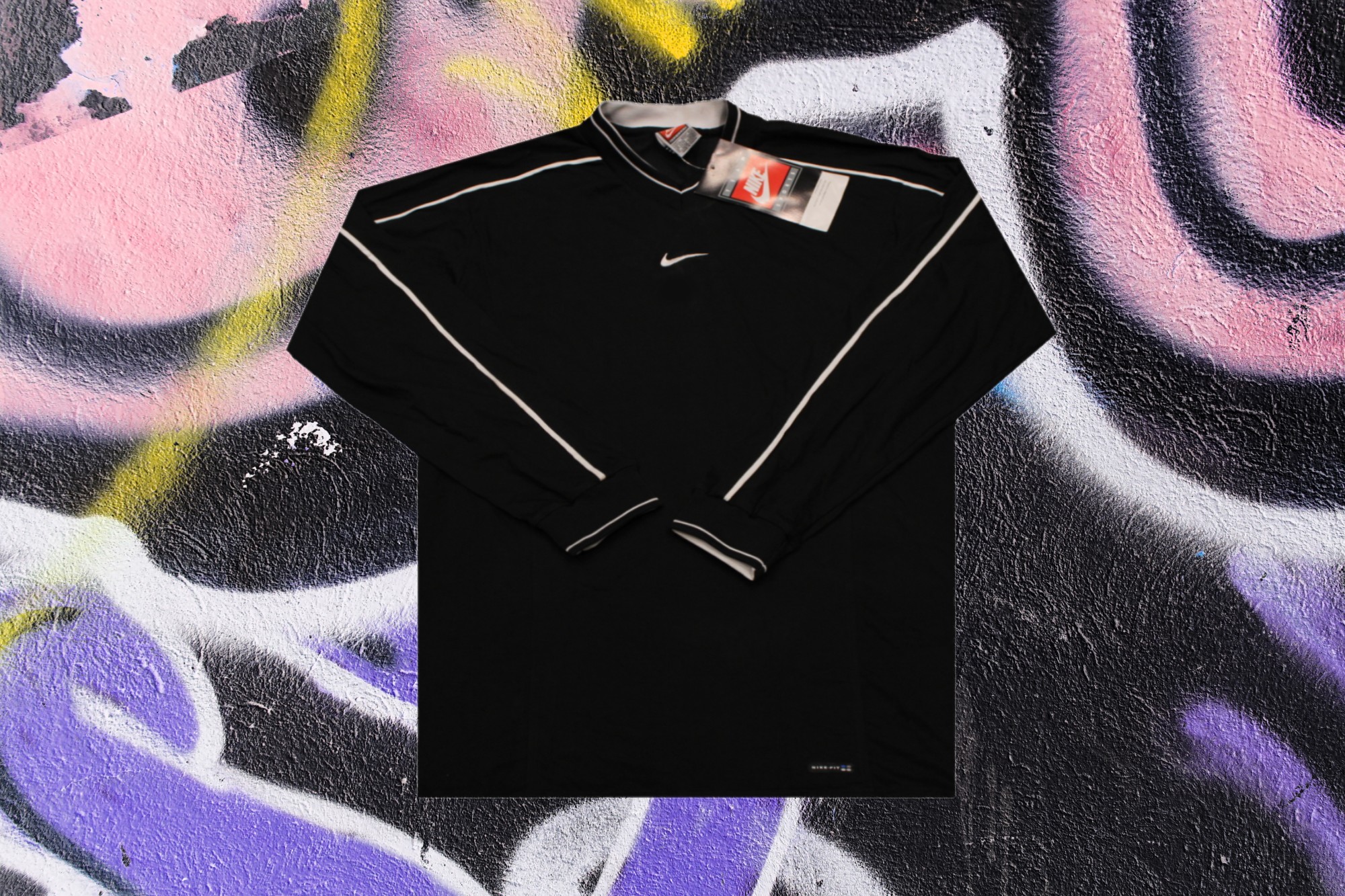 A vintage black Nike football shirt laid out against a colourful wall